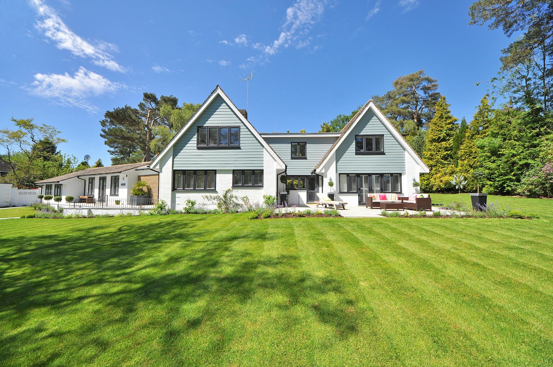 pexels-photo-280222-280222-2 Modern family home exterior showcasing a large lawn and garden under a clear blue sky.
